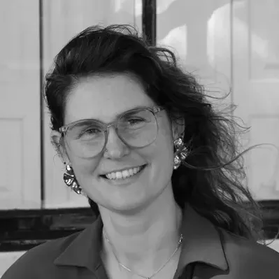 Gabrielle staat voor raam en kijkt terug in zwart-wit